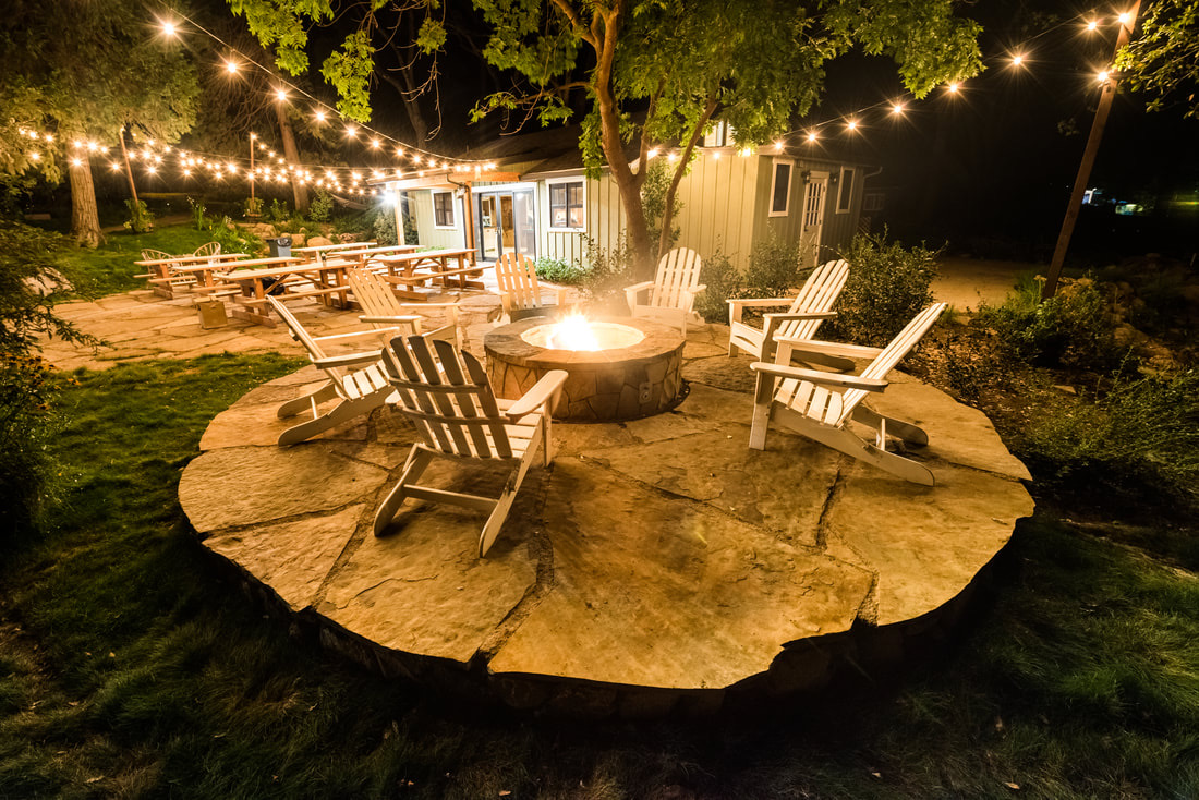 A fire pit with chairs around it in the middle of an area.